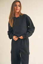 Woman wearing a black cropped fleece sweatshirt and matching black pants in casual women's clothing style