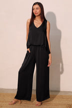 Woman wearing a black sleeveless V-neck top paired with wide-leg pants in women's clothing fashion.