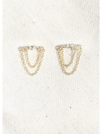 Gold vermeil earrings with two delicate chains and small clear baguette stones on a cream fabric background
