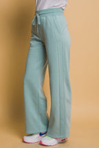 Light blue wide sweatpants with drawstring waist, shown on a woman wearing white sneakers and a white top.