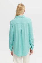 Woman wearing a sea-colored long sleeve blouse made of soft breathable fabric, shown from the back
