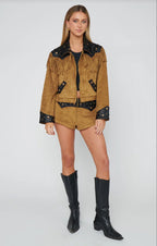 Woman wearing brown suede fringe shorts and matching jacket with black boots styled for a western festival look