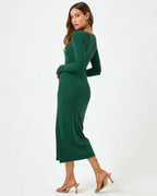 Woman wearing a long-sleeve green midi dress with square neckline and side slit, styled for fall and winter events