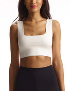 Woman wearing white sleeveless square neck crop top paired with black high-waisted bottoms in fashion apparel style