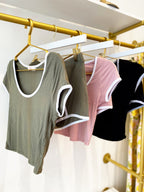 Assorted women's scoop neck ringer tees and matching boy shorts in soft, stretchy rib fabric hanging on a rack.