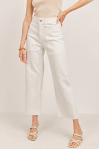 Woman wearing white wide leg pants with large front pockets and a fitted beige sleeveless top