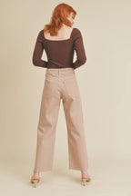Woman wearing beige wide leg pants and dark brown fitted long sleeve top viewed from behind