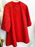Red textured women's coat with rhinestone button closure and three-quarter sleeves on a hanger.