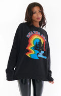 Woman wearing oversized black sweatshirt with colorful vintage graphic of trees and rainbow shapes